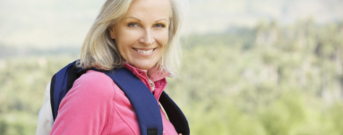 Senior woman in pink jacket carrying a backpack